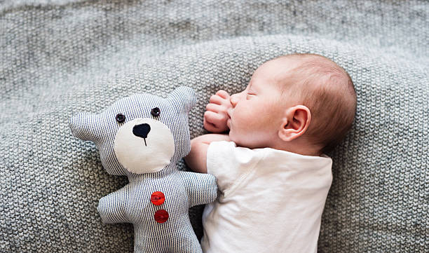 neonato sdraiato a letto con orsacchiotto, addormentato - teddy bear baby toy stuffed animal foto e immagini stock