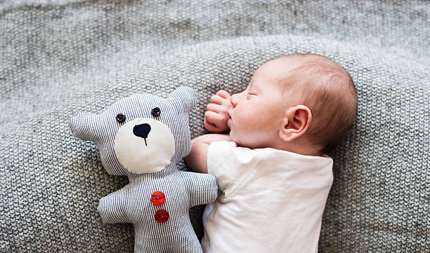 Newborn baby boy lying on bed with teddy bear, sleeping Cute little newborn baby boy lying on bed with his teddy bear, sleeping, close up teddy bear photos stock pictures, royalty-free photos & images
