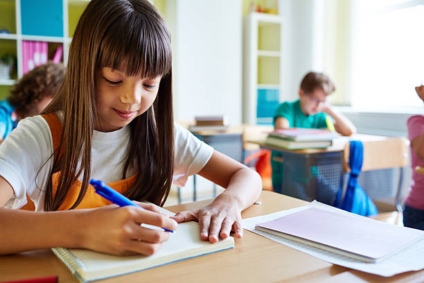 istock Schoolgirl writing in copybook 625687276