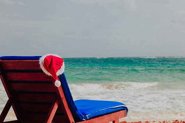 istock chair lounge with red Santa hats on tropical beach 625687314