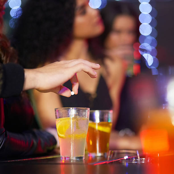 Closeup shot of a man drugging a woman's drink in a nightclub