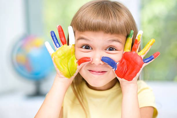 Portrait of a cute girl playing with paints stock photo