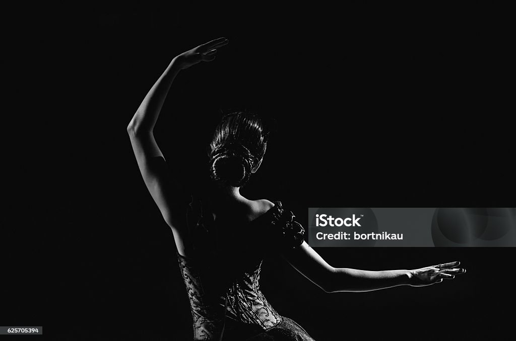 Silhouette of young ballet dancer standing back to camera Light silhouette of elegant young ballerina standing back to camera in third position arms petite pose on the black background Ballet Stock Photo