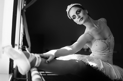 Beautiful young ballerina ballet dancer warming up and stretching trains in the dance studio