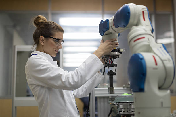Female engineers working with robotic arm Mid adult female engineers working with robotic arm robotic arm lab stock pictures, royalty-free photos & images