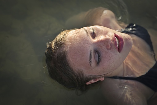 Portrait of a beautiful young girl enjoying having bath in the sea in her black bikini.