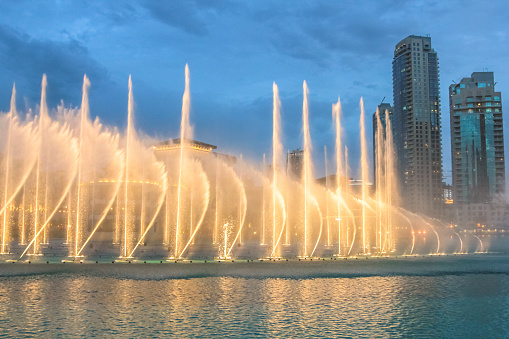 Night view of the light show at Dubai Dancing Fountain. The Dubai Fountain, the world largest choreographed fountain on Burj Khalifa Lake area, performs to the beat of the selected music.