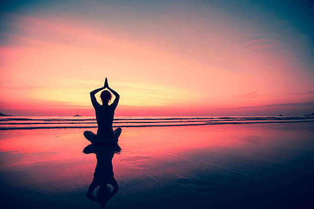 istock Silhouette young woman practicing yoga on the beach at sunset. 625723036