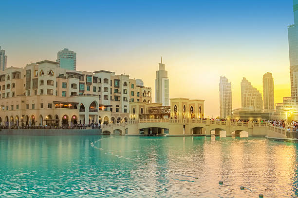 Burj Khalifa Lake Dubai Scenic view of Burj Khalifa Lake, a pool where they dance the Dubai Fountain. On background, the bridge that connects the Dubai Mall to Souk Al Bahar. People crowd around the shopping area at sunset. dubai mall stock pictures, royalty-free photos & images