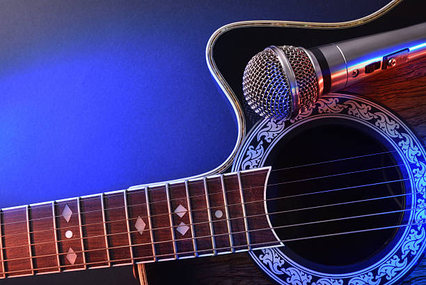 istock Acoustic guitar and microphone isolated with red and blue lights 625724650