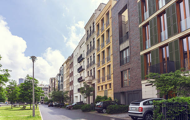 Car parked in front of an urban apartment block with a view down the road lined with multiple residential flats in a receding perspective