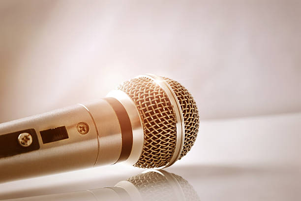 istock Microphone with golden reflections on a white glass table closeu 625725834