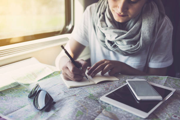 mujer joven planeando un viaje, usando el teléfono inteligente, viajando en tren - bus coach bus travel red fotografías e imágenes de stock