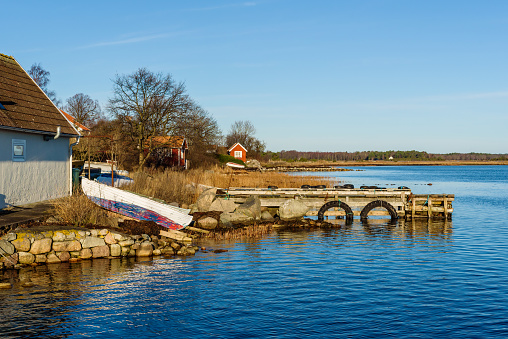 Pulled up wooden rowboats in coastal landscape in fall. Boathouses in background. Kristianopel in Sweden.