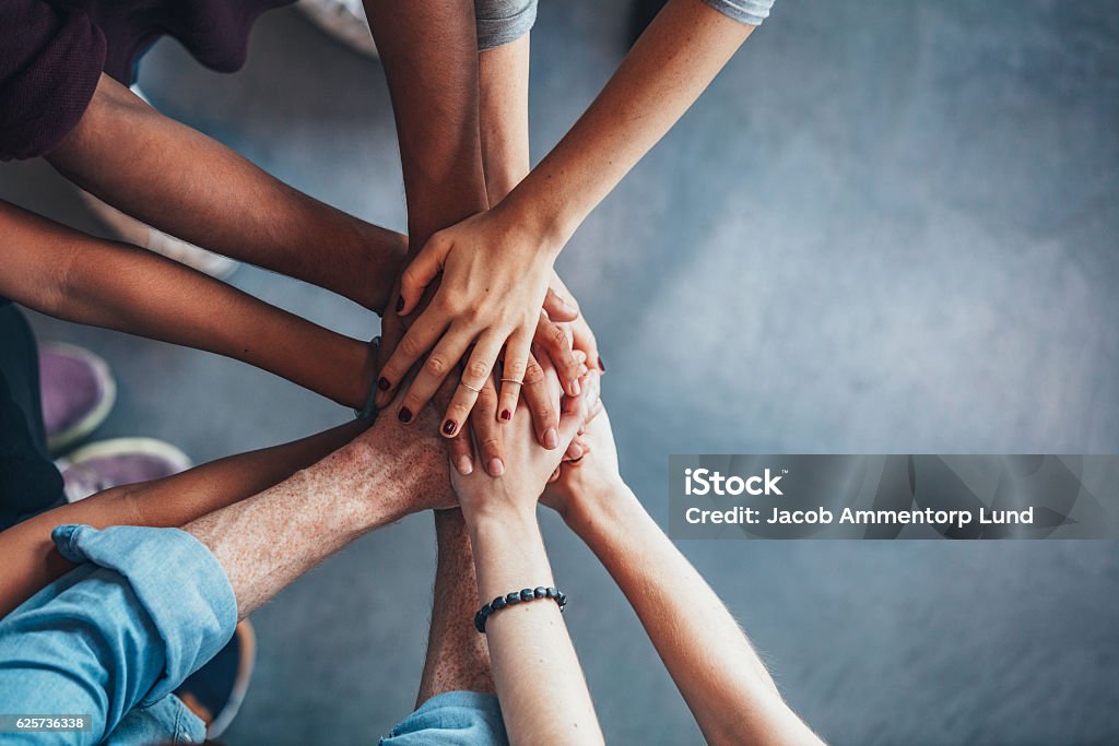 Stack of hands showing unity Close up top view of young people putting their hands together. Friends with stack of hands showing unity. Teamwork Stock Photo