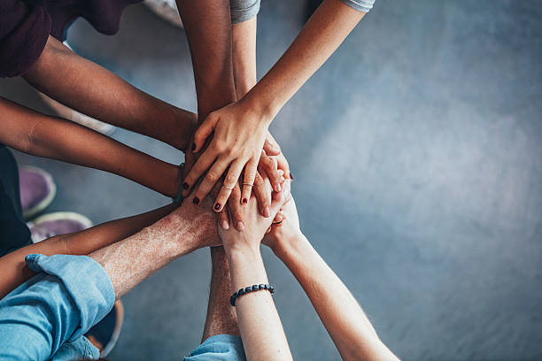 Stack of hands showing unity Close up top view of young people putting their hands together. Friends with stack of hands showing unity. togetherness stock pictures, royalty-free photos & images