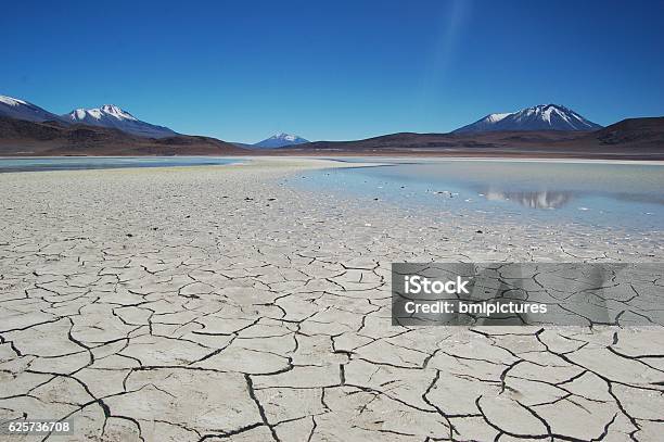 Sequía Lago Seco Agrietado Rodeado De Montañas Y Cielo Azul Foto de stock y más banco de imágenes de Nieve