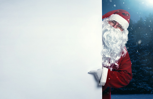 Santa Claus pointing on blank wall, advertisement banner with copy space
