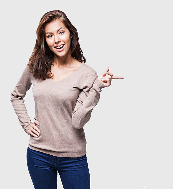 Young woman pointing at copy space Young beautiful woman pointing at copy space women satisfaction decisions cheerful stock pictures, royalty-free photos & images