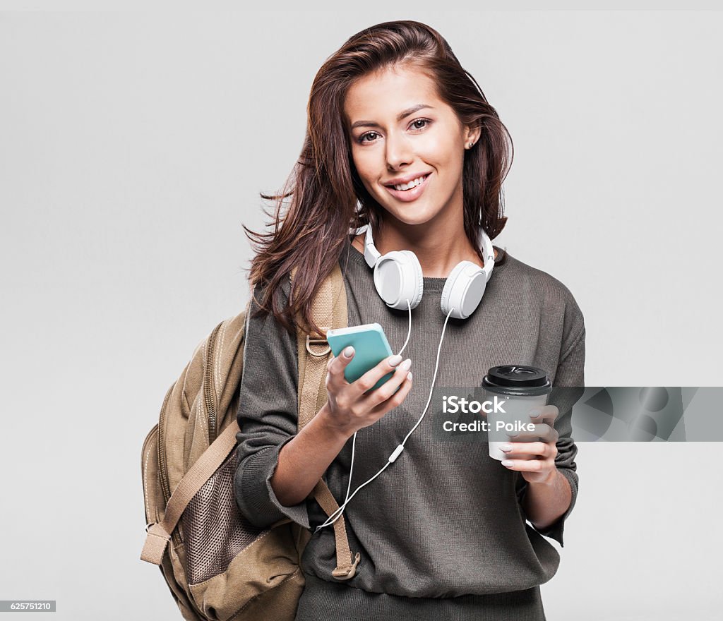 Happy young student girl using smart phone Happy young tourist girl holding smartphone and coffee Women Stock Photo