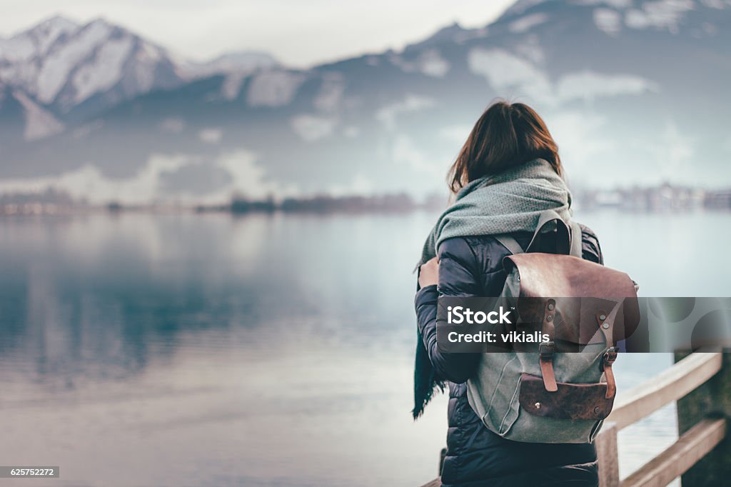 Traveler looks at landscape Hipster young girl with backpack enjoying landscape standing near the lake. Travel Stock Photo