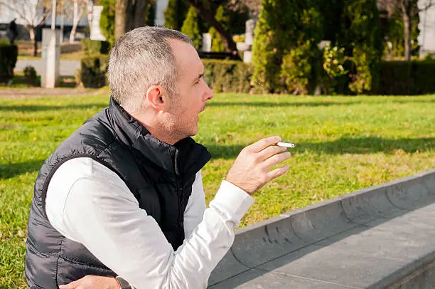 Photo of handsome man smoking a sigarette outdoor in a sunny day