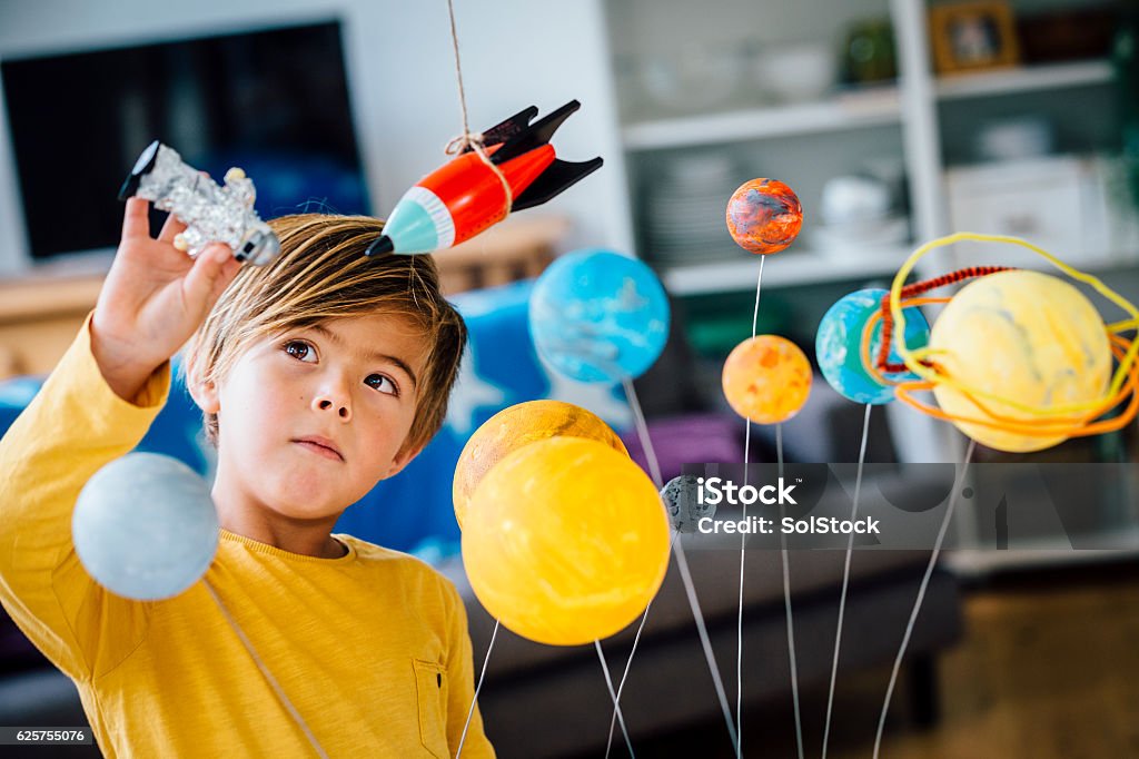 Playing with his Astronaut Little boy playing with his homemade planetarium as he holds an astronaut. A rocket hangs above. Arms raised as he plays. Child Stock Photo