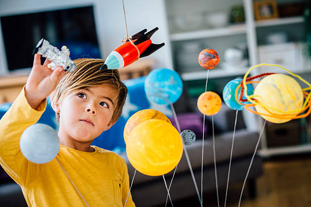 Playing with his Astronaut Little boy playing with his homemade planetarium as he holds an astronaut. A rocket hangs above. Arms raised as he plays. 6 7 years stock pictures, royalty-free photos & images