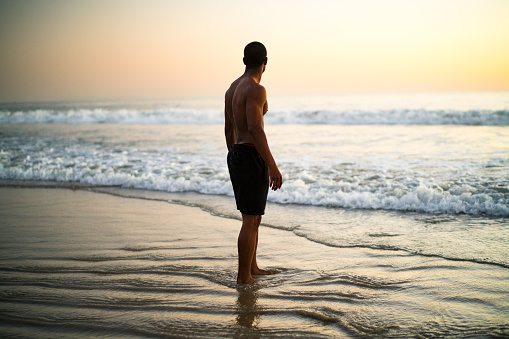 Silhouette of adult man walking on beach during sunrise. Cabo de Gata Nature Park, Almeria, Spain