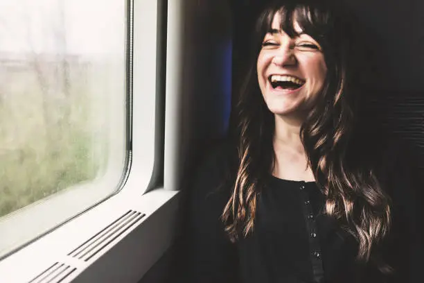 Young woman on the window seat, laughing.