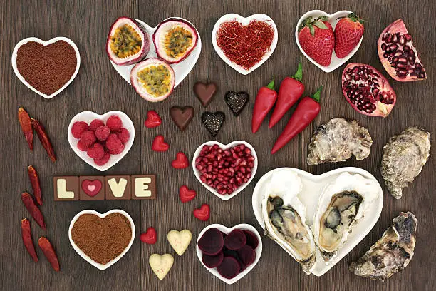 Aphrodisiac food for sexual health with foods in heart shaped bowls and loose on oak wood background.