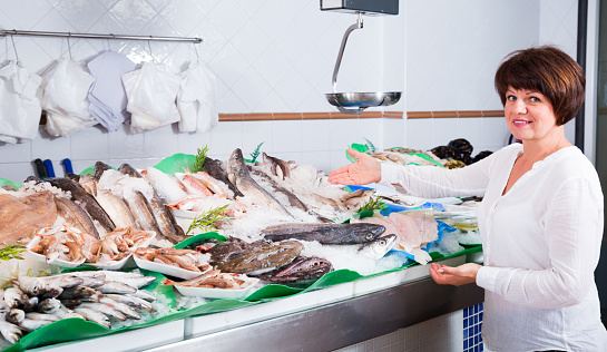Woman choosing fish in store and smiling