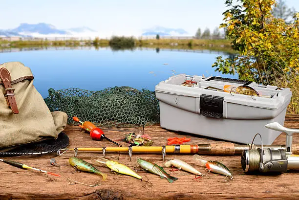 Fishing equipment on a wooden table with lake in background