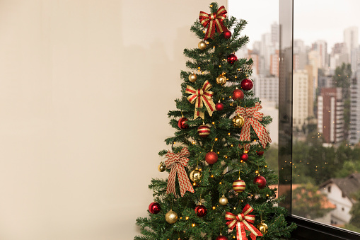 Christmas tree in daylight, with a city landscape in the background