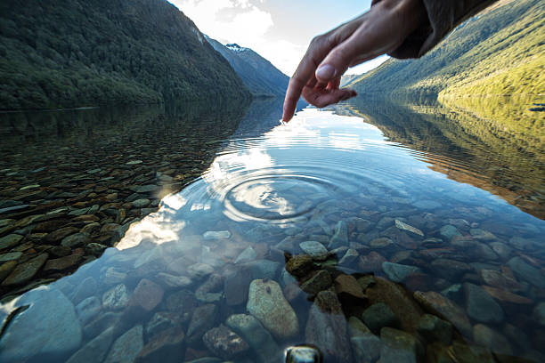istock Finger touches surface of mountain lake 625793090