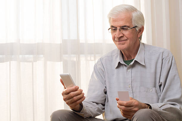 older man using credit card - glasses holding business card imagens e fotografias de stock