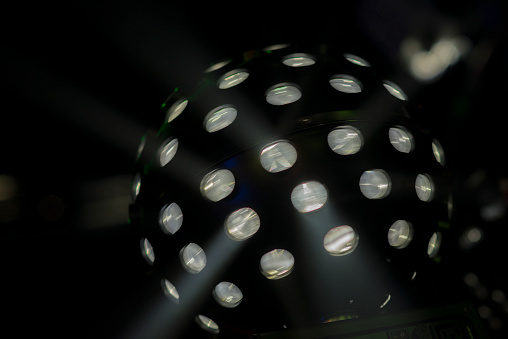 Bright coloured moving white disco lightball shot in darkened nightclub  setting