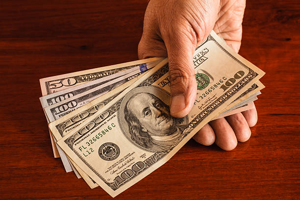 istock Dollars, USA currency - Not the minimum wage. 100 Dollar Bills And A Single $50 Note Against A Rosewood Background. 625796316