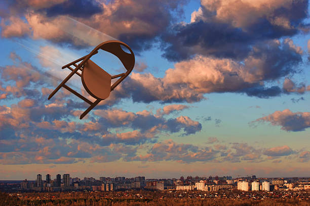 Brown - orange chair motion on background of urban landscape, blue sky, pyellow pink clowds. 