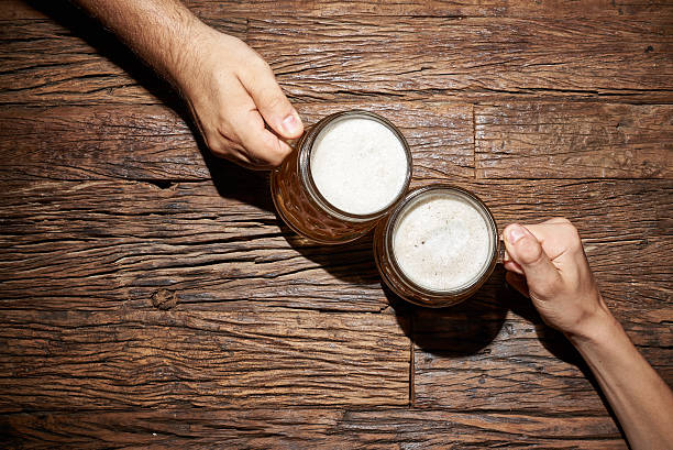 Beer mug Male hands with beer mug on an old wooden table top honor stock pictures, royalty-free photos & images