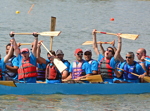 Denver, CO, USA - July 31, 2016: Over 110,000 people attended the 16th Annual Colorado Dragon Boat Festival and enjoyed the exciting dragon boat races as well as all the numerous demonstrations, vendors and delicious foods. Unidentified team competing in the exciting boat races raise their oars in victory. 