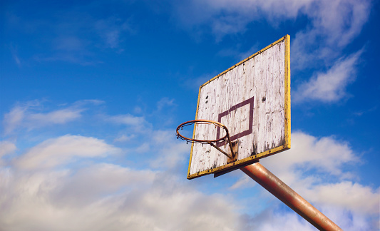 Old wooden basketball board in blue cloudy sky background