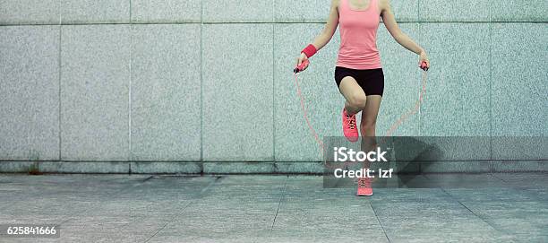 Young Fitness Woman Rope Skipping Against City Wall Stock Photo - Download Image Now