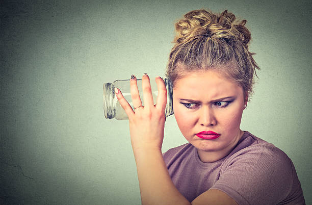 mulher intrometida com jarra de vidro ouve fofocas atrás da parede - rudeness whispering gossip humor - fotografias e filmes do acervo