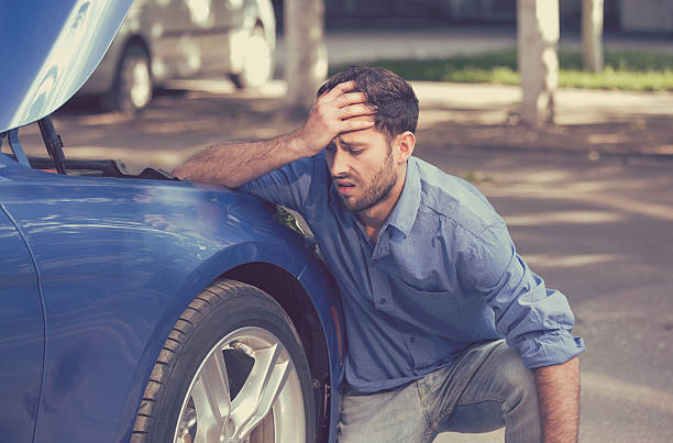 Man with broken down car flat tire Man with broken down car flat tire in the middle of the street vehicle breakdown stock pictures, royalty-free photos & images