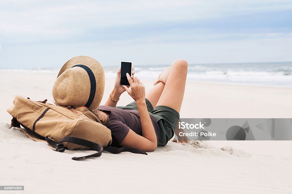 Mujer usando teléfono inteligente en la playa - Foto de stock de Playa libre de derechos