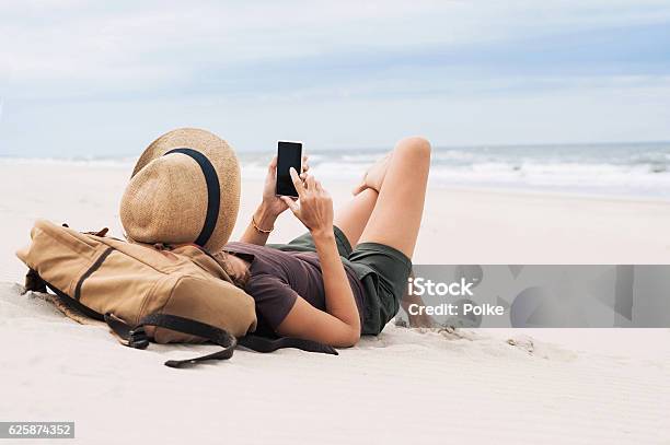 Mujer Usando Teléfono Inteligente En La Playa Foto de stock y más banco de imágenes de Playa - Playa, Teléfono, Vacaciones - Viaje