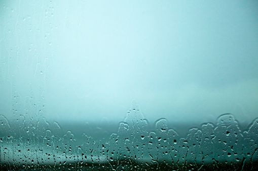 Seascape through the window in a rainy day. Horizon over water, copy space available on the upper side of the image, on moody sky.