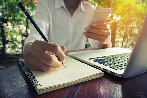 istock Woman write on notebook and holding mobile phone vintage tone. 625877624