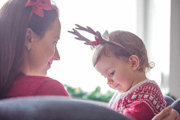Family day happy family mother and little daughter playing in Christmas.Reindeer antlers and oily on their heads.Behind  Christmas and New Year decorations.Mother and  daughter enjoying the holidays at home baby new years eve new years day new year stock pictures, royalty-free photos & images